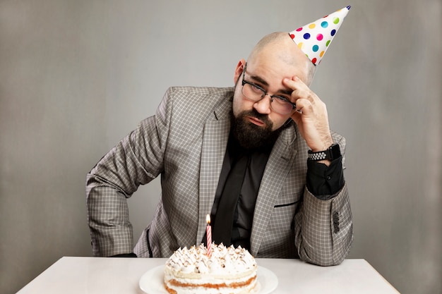 Homme Triste Dans Un Chapeau De Carnaval Avec Un Gateau Avec Une Bougie Fete Noire Photo Premium