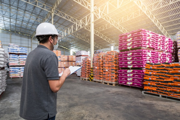 Un homme vérifie la qualité du produit dans l'entrepôt. entreposage, contrôle de qualité Photo Premium