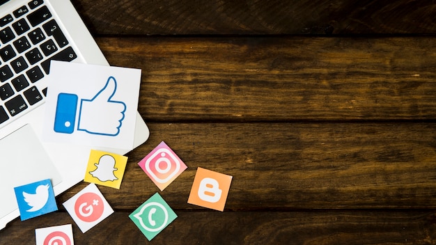 Icônes de médias sociaux avec comme icône sur ordinateur portable sur fond en bois Photo gratuit