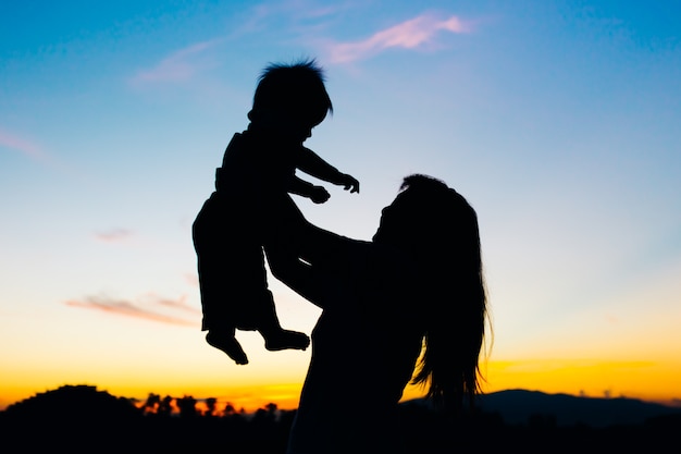 Une Image De La Silhouette De La Mere Tenant Son Bebe Tandis Que Le Ciel Du Coucher Du Soleil Et Du Crepuscule Photo Premium