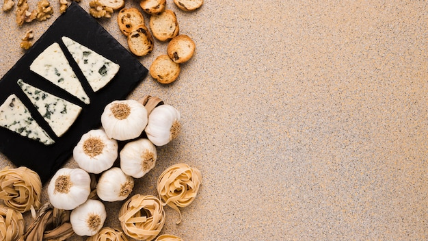 Ingrédients frais et tranches de fromage gorgonzola sur un plateau en ardoise recouvrant une surface texturée Photo gratuit