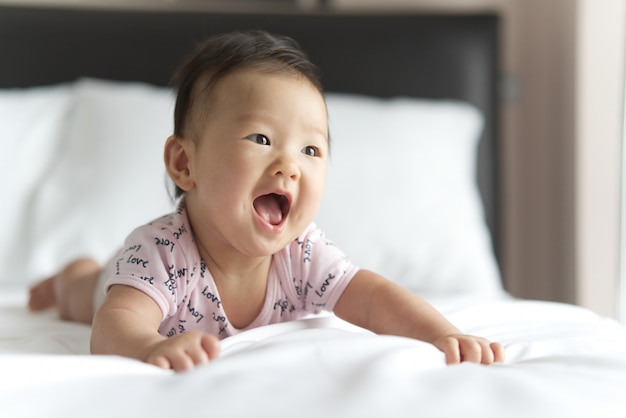 Jeune Bebe Asiatique Mignon Rampant Sur Le Lit Dans La Chambre Le Bebe Sourit Et Regarde Droit Photo Premium