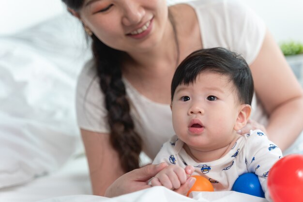 Jeune Belle Mere Asiatique Avec Bebe Asiatique Sur Le Lit Et Jouer A La Balle De