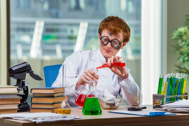 Jeune chimiste fou travaillant dans le laboratoire Photo Premium