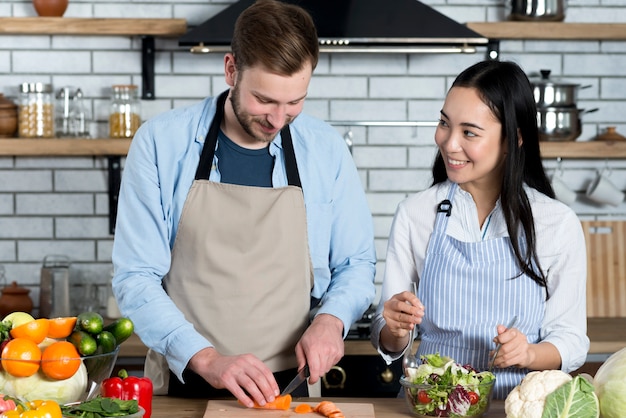 Jeune couple s'amuser tout en préparant un repas dans la cuisine Photo gratuit