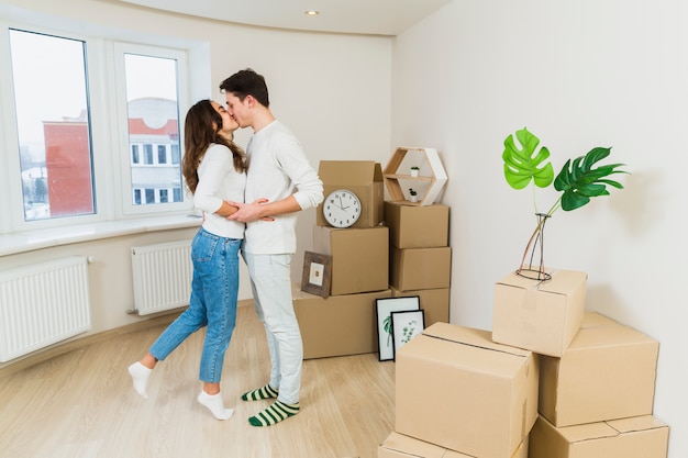 Jeune couple s'embrassant avec des boîtes en carton dans leur nouvelle maison Photo gratuit