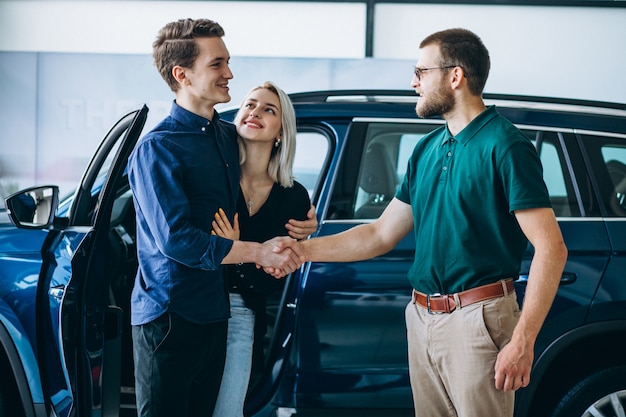 Jeune famille achète une voiture dans une salle d'exposition Photo gratuit