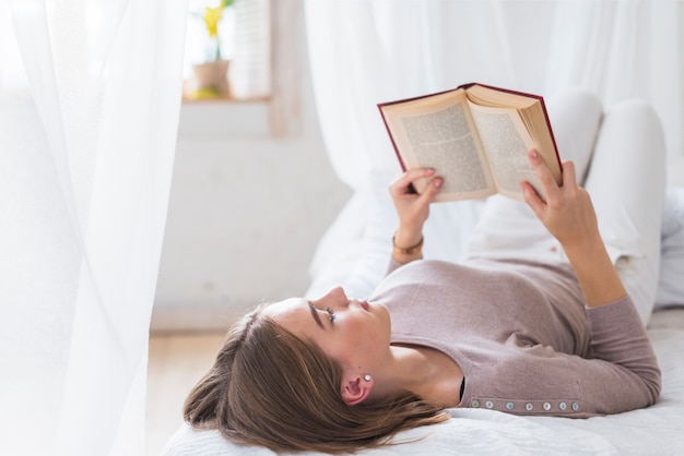 Jeune Femme Allongée Sur Le Lit Livre De Lecture Photo Gratuite 