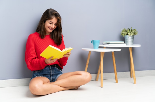 Jeune femme assise sur le sol et tenant un cahier Photo Premium