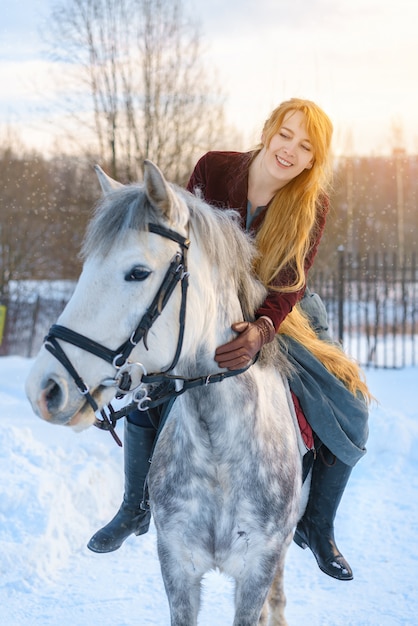 Jeune femme aux cheveux longs à cheval en hiver Photo Premium