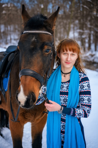 Jeune femme aux cheveux rouges sur un cheval en hiver Photo Premium