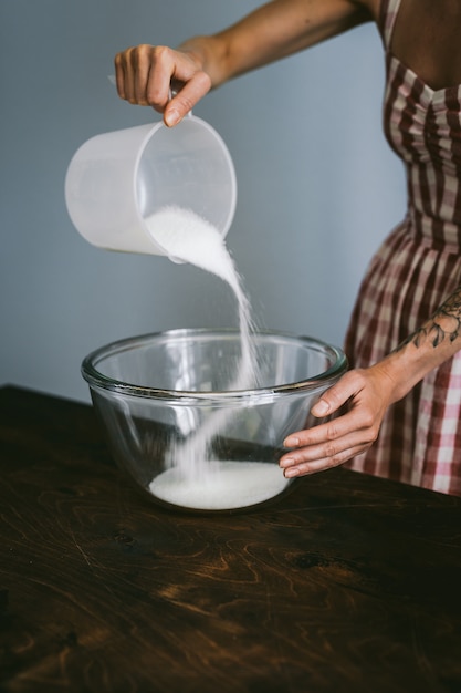 Jeune Femme Dans Une Robe A Carreaux Rouge Et Blanc Cuire Un Gateau Ajouter Du Sucre Dans Un Grand Bol En Verre Photo Premium