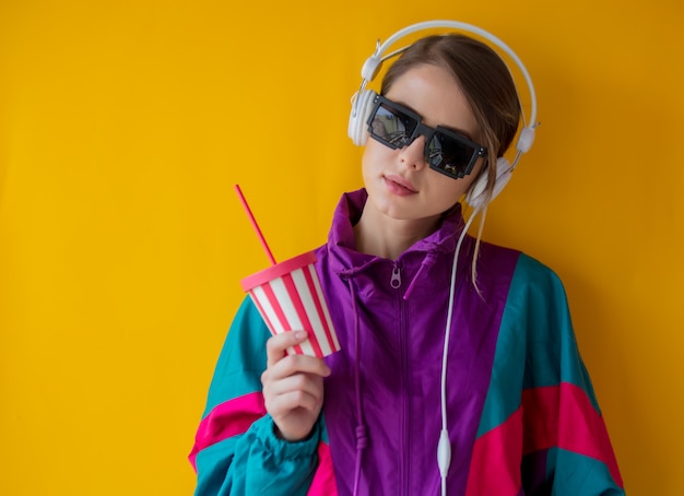 Jeune femme dans le style des années 90 avec une tasse et des écouteurs Photo Premium