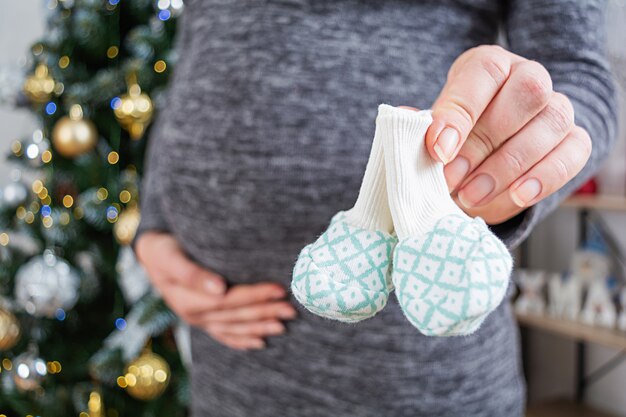 Jeune Femme Enceinte Avec Ventre Gonfle Et Chaussettes Bebe Dans Sa Main Posant Contre L Arbre De Noel Photo Premium