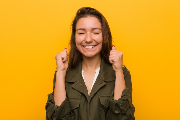 Jeune femme européenne isolée sur jaune levant le poing, se sentir heureuse et réussie. Photo Premium