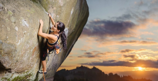 Jeune femme grimpeur attrayant escalade voie difficile sur une paroi rocheuse escarpée Photo Premium