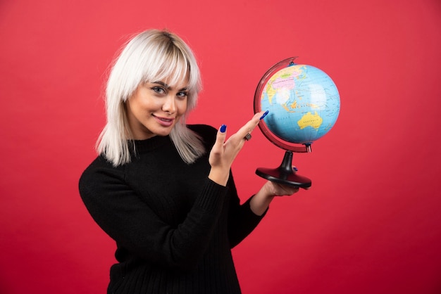 Jeune Femme Montrant Un Globe Sur Fond Rouge. Photo De ...