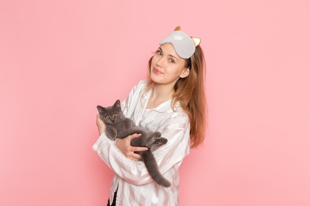 Jeune Femme En Pyjama Et Masque De Sommeil Posant Avec Chaton Sur Rose Photo Gratuite