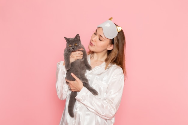 Jeune Femme En Pyjama Et Masque De Sommeil Tenant Un Chat Mignon Sur Rose Photo Gratuite