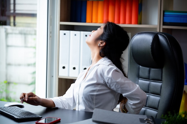 Jeune femme qui travaille mal au dos pendant le travail Photo gratuit