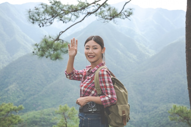 La jeune fille fit un signe de la main au sommet de la colline dans une forêt tropicale avec des sacs à dos dans la jungle. aventure, randonnée. Photo gratuit