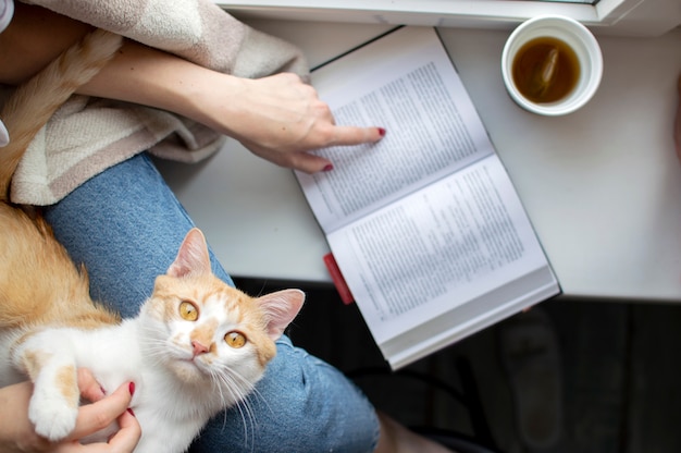 Jeune Fille Recouverte D Une Couverture Est Assise A La Fenetre Avec Son Chat Lit Un