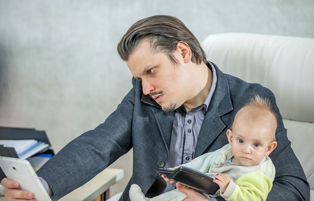 Jeune Homme D Affaires Travaillant Depuis Son Bureau Et Tenant Un Bebe Photo Gratuite