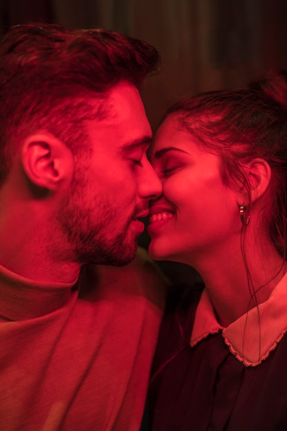 Jeune homme embrasse une femme souriante dans la rougeur Photo gratuit