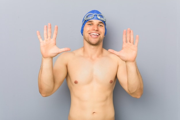 Jeune homme nageur professionnel montrant le numéro dix avec les mains. Photo Premium