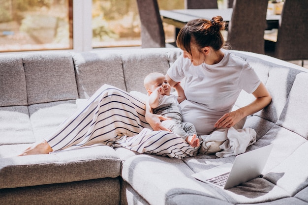 Jeune Maman Avec Son Enfant Travaillant La Maison Sur Un Ordinateur Photo Gratuite