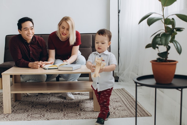 Jeune Papa Asiatique Et Maman Blonde Europeenne Jouent Assis Avec Son Fils Dans Une Salle Lumineuse Photo Premium