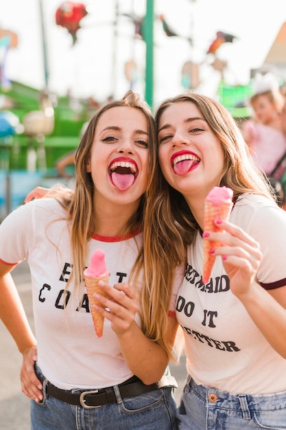 Jeunes amis, manger des glaces dans le parc d'attractions Photo gratuit