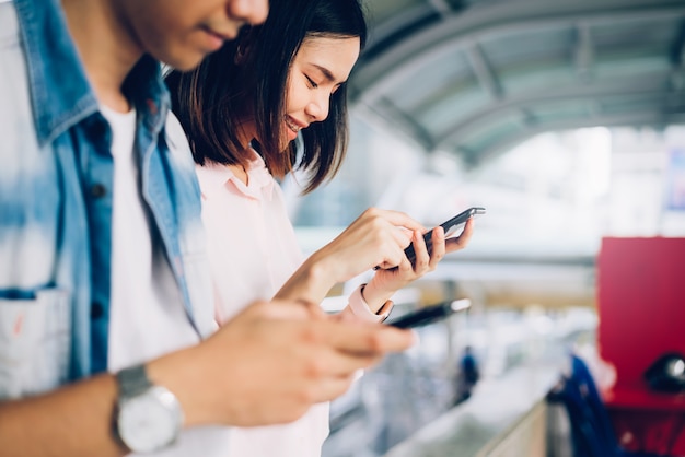 Les jeunes utilisent un smartphone et sourient lorsqu'ils sont assis sur leur temps libre. Photo Premium