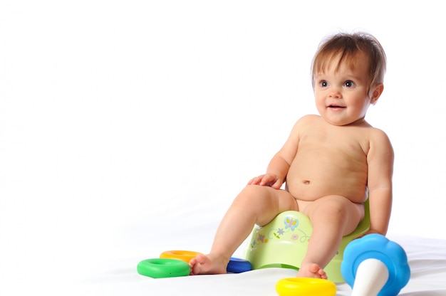 Joli Petit Bebe Est Assis Sur Un Pot Vert Et Joue Au Jouet Aime Photo Premium