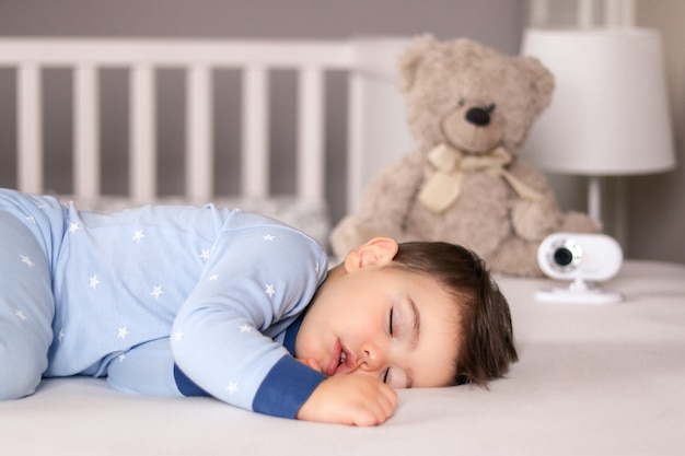 Joli Petit Bebe Garcon En Pyjama Bleu Clair Dormant Paisiblement Sur Le Lit Avec Moniteur Pour Bebe Photo Premium