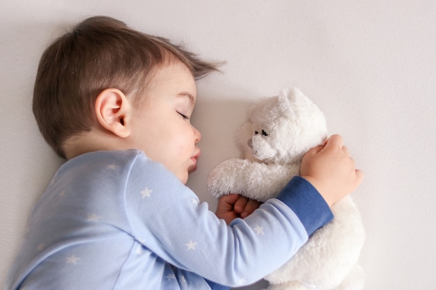 Joli Petit Bebe Garcon En Pyjama Bleu Clair Endormi Etreignant Un Jouet Blanc D Ours En Peluche Photo Premium