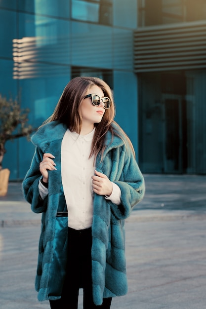 Jolie adolescente vêtue d'un manteau de fourrure naturelle coloré vif et de lunettes de soleil Photo Premium