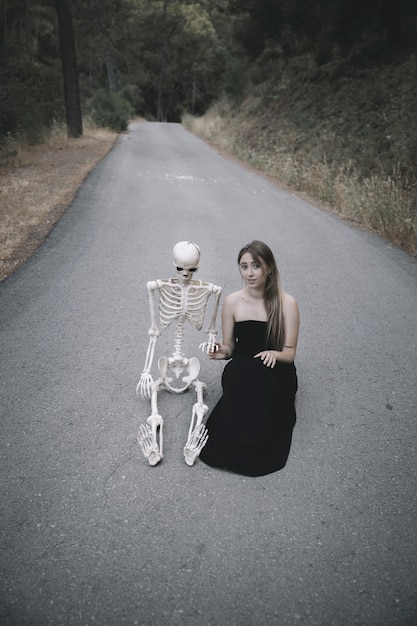 Jolie Femme  Assise Sur La Route Avec Un Squelette  