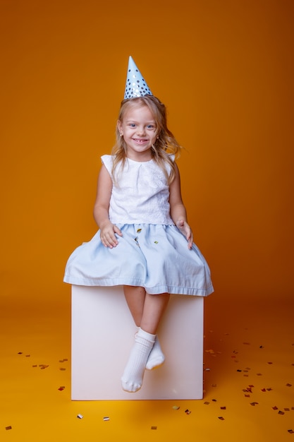 Joyeux Anniversaire Bebe Fille Avec Des Confettis Colores Sur Fond Jaune Assis Sur Un Cube Blanc Photo Premium