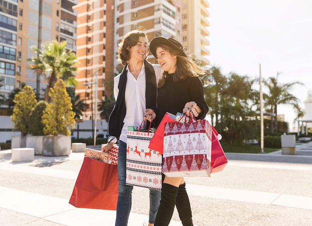 Joyeux couple marchant avec des sacs de noël Photo gratuit