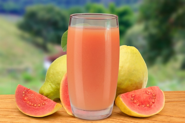 Jus de goyave frais dans une coupe en verre sur une table en bois de la nature et de la ferme Photo Premium