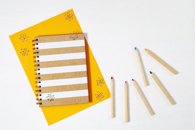 Lay plat avec des crayons de couleur en bois, cahier de mode pour écrire et dessiner sur l'espace de travail de table avec espace de copie. fournitures de peinture. vue de dessus. Photo Premium