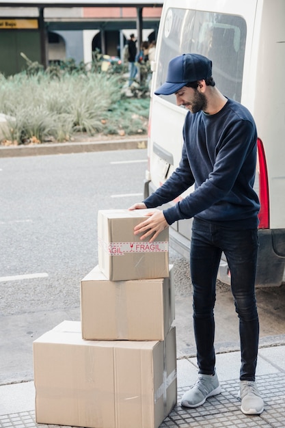 Livrer Un Homme En Regardant Des Boîtes En Carton Empilées Photo Gratuite