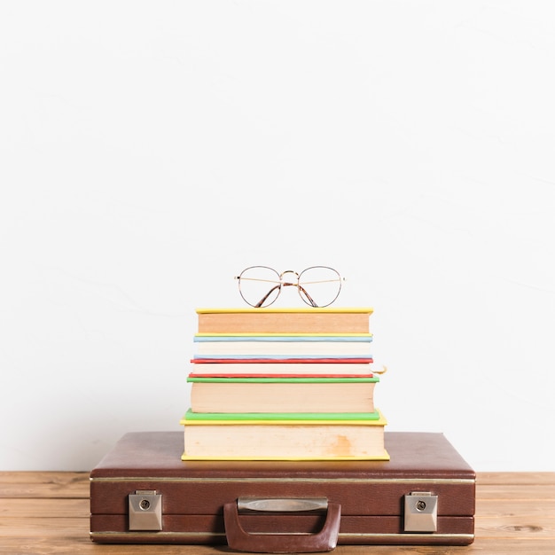 Lunettes classiques sur une pile de livres sur une valise vintage Photo gratuit