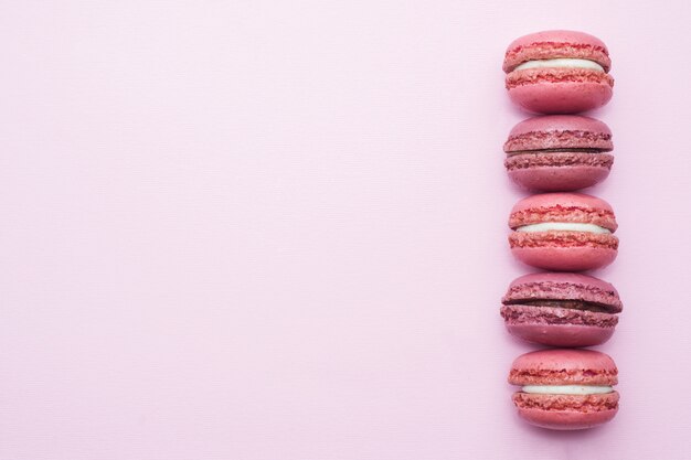 Macaron dessert rose ou macaron sur la vue de dessus de fond rose avec plat poser Photo Premium