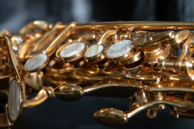 Macro de saxophone ténor doré avec mise au point sélective sur fond noir Photo Premium