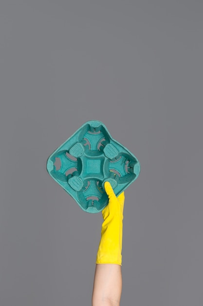 Main dans un gant en caoutchouc jaune pour le nettoyage est titulaire d'un carton vert Photo Premium