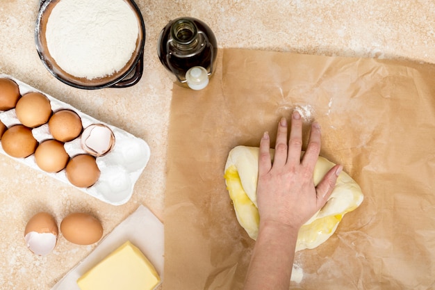 Main de femme en train de pétrir la pâte avec de l'huile sur papier parchemin Photo gratuit