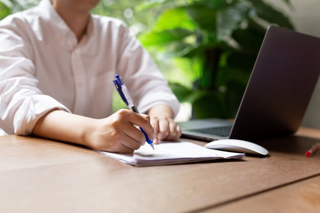 Main remplir le document sous forme de contrat avec un ordinateur portable une souris sur une table en bois. Photo Premium