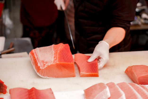 Mains d'un chef japonais utilisant un couteau en tranches de thon frais pour le vendre au client au marché aux poissons du matin, japon. Photo Premium